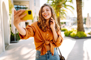 Young woman walks the streets and takes selfie using smartphone camera. Beautiful young...