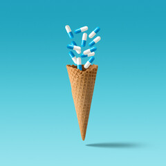 Creative concept with capsule pills and waffle cone on bright background. Minimal medical concept.