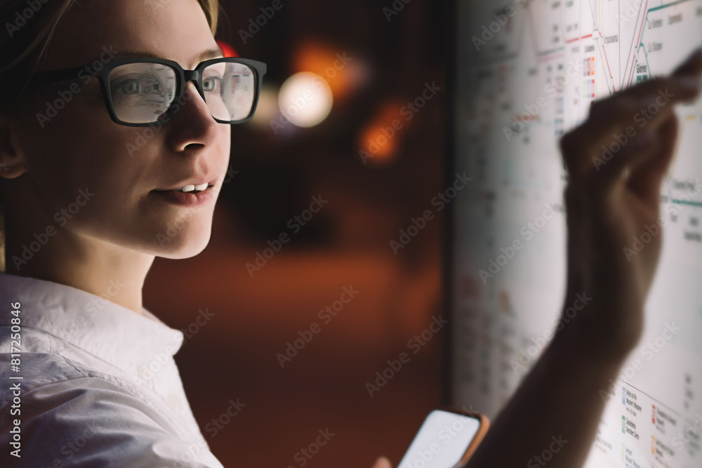 Wall mural interactive kiosk with public transport subway map.female standing at big display with smartphone in