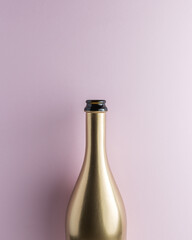 Golden champagne bottle on pink background. Minimal celebration concept.