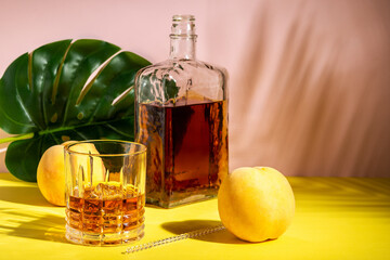 Alcoholic drink in a glass with a peach on a bright background. Summer party concept.