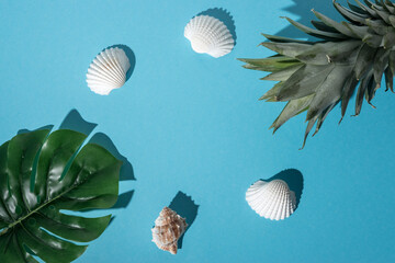 Creative composition with seashells, tropical palm leaf and pineapple on pastel blue background....