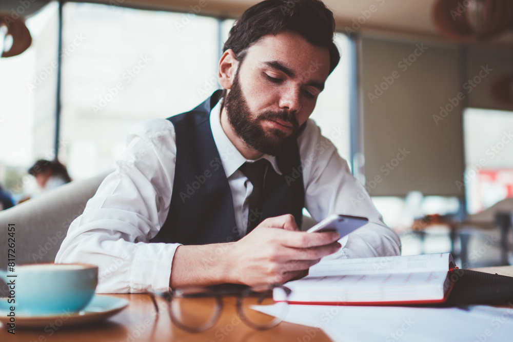 Poster bearded male blogger reading message from follover via telephone while creating new profile publicat