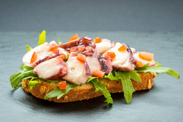 Close-up of typical Venetian cicchetti, featuring octopus, against a dark backdrop