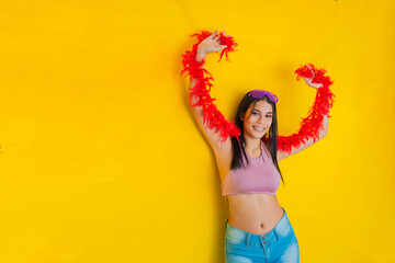 brunette latina woman, on a yellow background celebrating with her hands up, holding a strip of red...