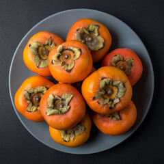 Delicious fresh persimmon fruits on black background.