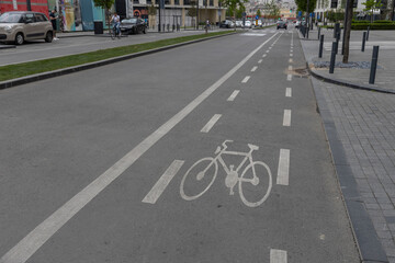 A well-marked bike lane on an urban road with clear road markings, a bicycle symbol, and white lines indicating the direction of traffic. The scene is devoid of people