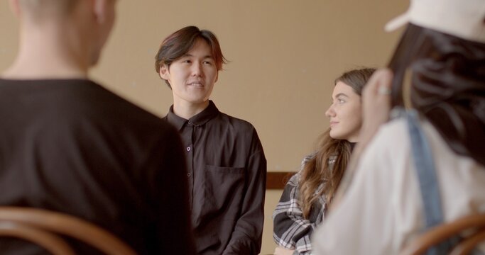 Person in club to improve public speaking, presentation. Debate Clubs background. Asian Man practice presenting arguments, open to feedback. Communication development and speech improvement of people.