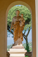 Antique Roman life-size sculpture made of white stone of a man with a beard holding a child in his arms, under an arch
