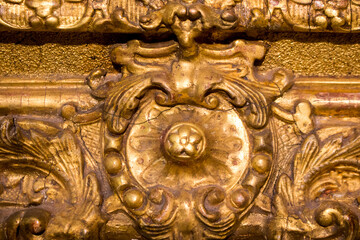 Fragment of an ancient gold picture frame, wood carving close-up. An expensive antique frame.