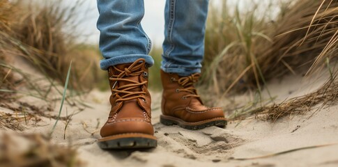 a man wearing brown boots walking on the beach