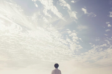 Person standing alone looking at a cloudy sky