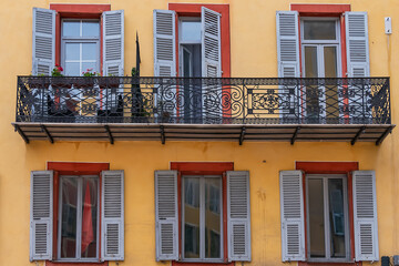 Fototapeta premium Architectural fragments of the facades of ancient houses in Nice: beautiful windows, balconies, shutters. Nice, capital of the Alpes-Maritimes department on the French Riviera.