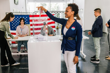 African American voter placing ballot in ballot box polling place in America