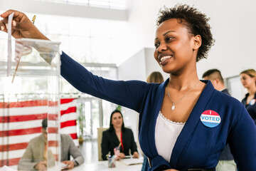 African American voter placing ballot in ballot box polling place in America