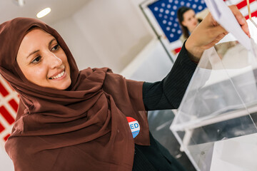 Muslim voter with hijab placing ballot in ballot box polling place in America.