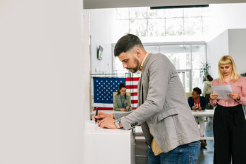 Voter placing ballot in ballot box polling place in America.