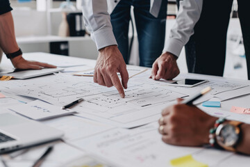 Team members discussing blueprints on a table in an office setting
