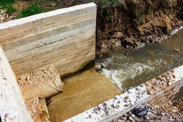A culvert under the road with a stream flowing through it