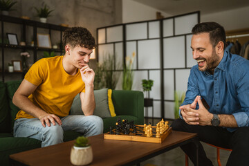 Two male friends brothers play chess together at home