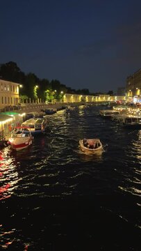 Russia, April 9, 2024: Boats on the canal in St. Petersburg in spring. Bridges and historical buildings on the river embankment, people walking along the embankment. Reflections of houses in the water
