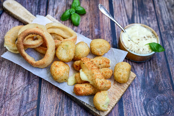 Selection of fast food snack. italian cheese breaded Mozzarella Sticks, Jalapeno Cheese nuggets, Onion Rings and mayo sauce.Italian street junk food