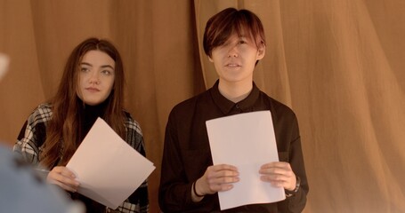 Portrait of a speaking Asian young man during theater mastery courses. Students hold scripts in...