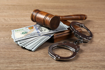 Judge's gavel, money and handcuffs on wooden table