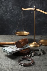 Judge's gavel, money, handcuffs and scales of justice on grey table