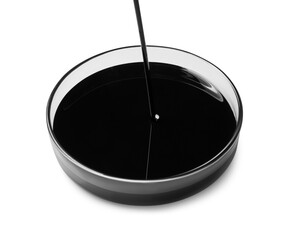 Pouring black crude oil into Petri dish on white background