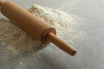 Flour and rolling pin on grey table, closeup