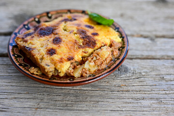 Bulgarian traditional moussaka Potato and minced meat  Casserole  with   parmesan cheese and garlic on wooden rustic bakcground.  