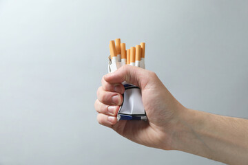 Stop smoking. Man holding pack with cigarettes on grey background, closeup