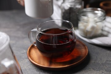 Tasty hot tea in cup on grey table, closeup