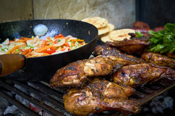 A plate of food with chicken, arepa and vegetables on a grill