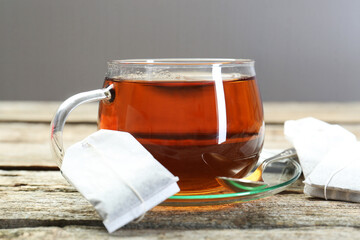 Aromatic tea in glass cup, spoon and teabags on wooden table