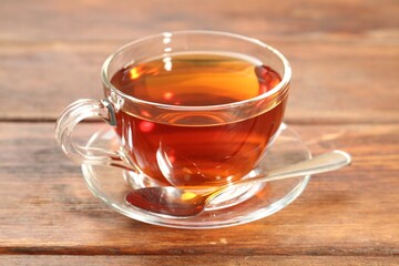 Glass cup of tea and spoon on wooden table