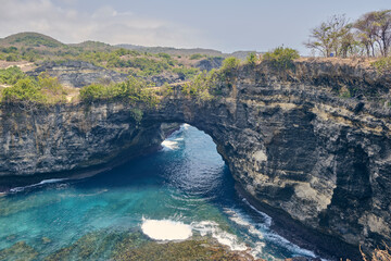 Broken beach in Nusa Penida, Bali, Indonesia. Blue Sky, Turquoise Water. Stone arch over the sea