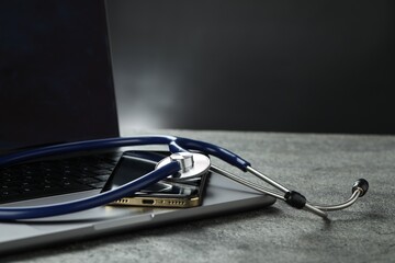 Modern electronic devices and stethoscope on grey table. Space for text