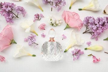 Luxury perfume and floral decor on white background, flat lay