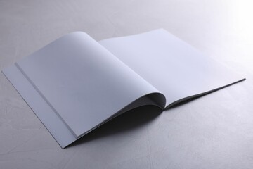 Open notebook with blank paper sheets on grey textured table. Mockup for design