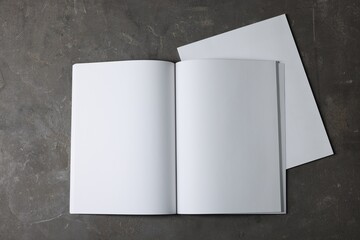 Open notebook with blank paper sheets on grey textured background, top view. Mockup for design