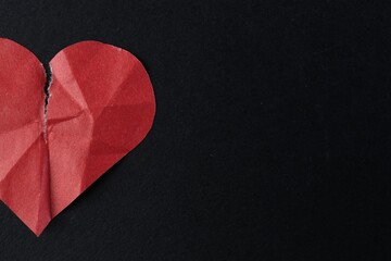 Crumpled torn paper heart on black background, top view with space for text. Breakup concept