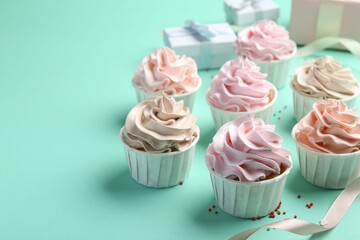 Delicious birthday cupcakes, ribbon and sprinkles on turquoise background, closeup. Space for text
