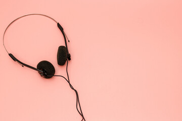 A pair of 1990's style headphones on a pink background retro vintage music concept image