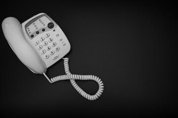 A black and white photo of a vintage style 1990's telephone on a black background, 90's technology...