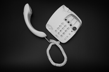 A black and white photo of a vintage style 1990's telephone on a black background, 90's technology...