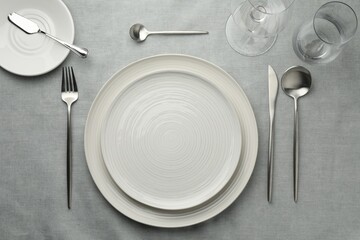 Stylish setting with cutlery, glasses and plates on grey table, flat lay