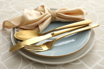 Stylish setting with cutlery, plates and napkin on table