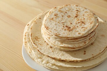 Many tasty homemade tortillas on wooden table, closeup
